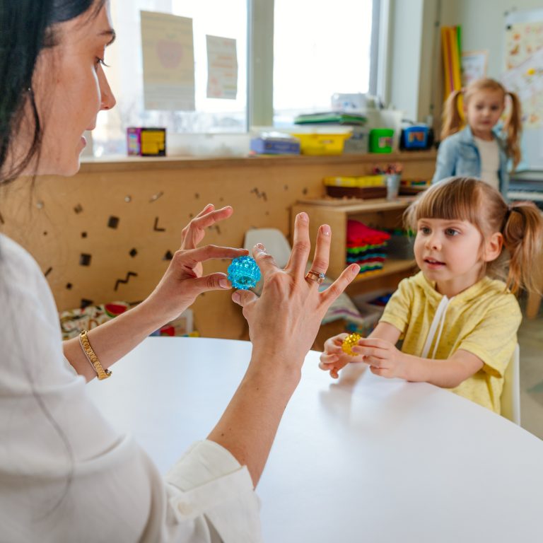 A teacher guiding a preschool student through an activity at Lighthouse Academy in Yorkville, focusing on one-on-one attention and development